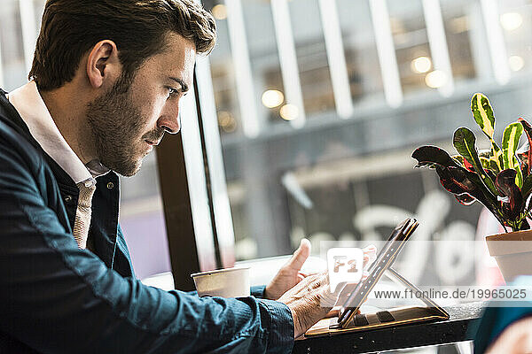 Businessman using tablet PC at cafe