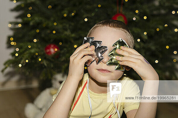 Boy covering eyes with Christmas decorations at home