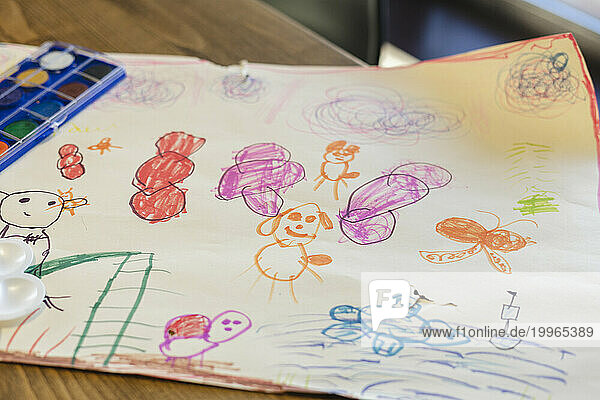 Paper with children drawing on table at home