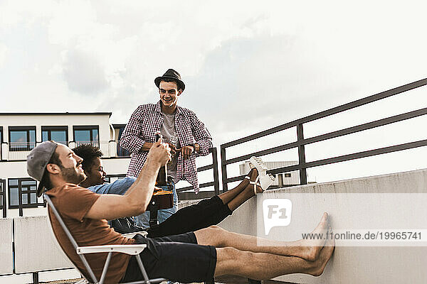 Friends having party with beer on rooftop under sky