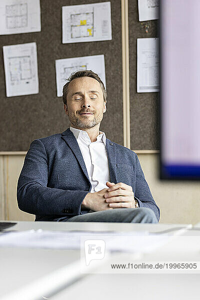 Businessman with eyes closed sitting at workplace
