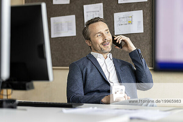 Mature businessman talking on smart phone in office