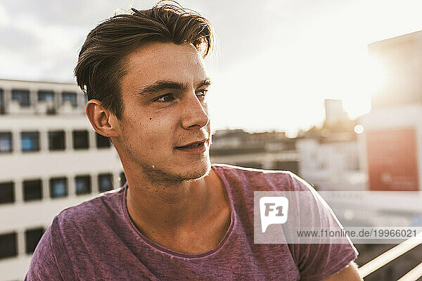 Thoughtful young man on rooftop at sunset