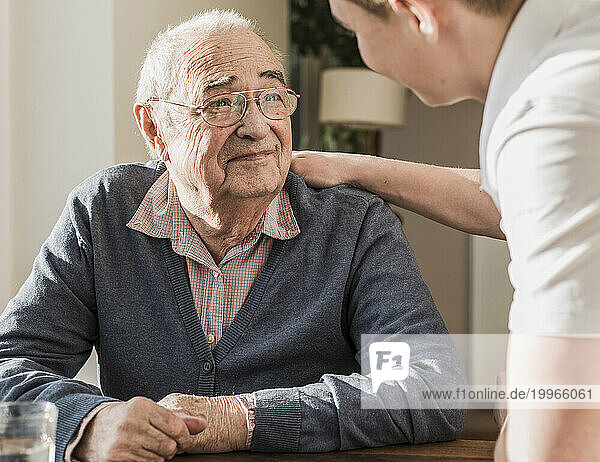 Young man taking care of grandfather at home