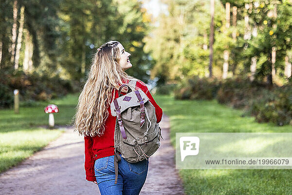 Happy woman walking with backpack on footpath in Cannock chase forest