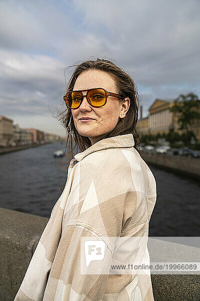 Smiling woman wearing sunglasses and standing near river