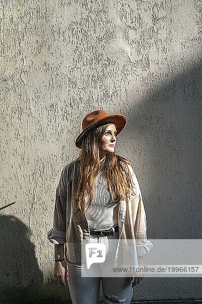 Woman wearing hat and standing in front of wall