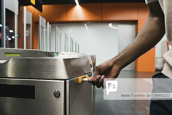 Hand of man inserting metro ticket in electronic barrier