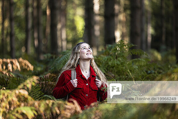 Smiling young woman standing amidst plants in Cannock chase forest