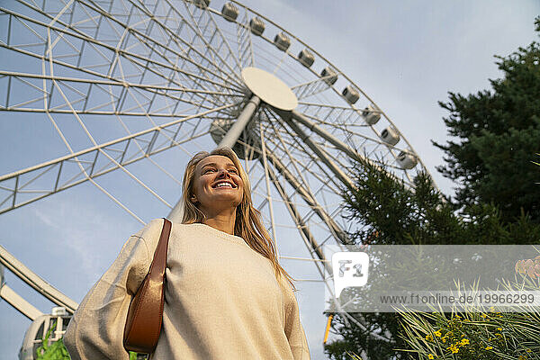 Happy woman standing in front of Ferris wheel