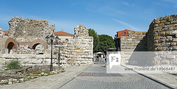 Touristen gehen auf einem Weg zwischen den Überresten einer alten Festung an einem sonnigen Tag  westliche Festungsmauer  Schwarzes Meer  Nesebar  Nessebar  Burgas  Bulgarien  Europa