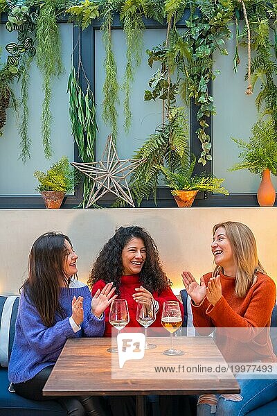 Feiernde und applaudierende Frauen beim Weintrinken in einem Restaurant
