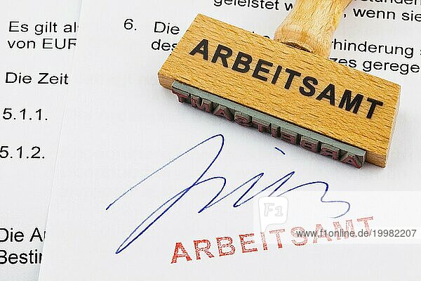 Ein Stempel aus Holz liegt auf einem Dokument. Deutsche Aufschrift: Arbeitsamt