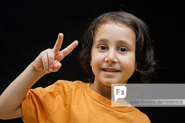 Lächelndes Kind mit glücklichem Gesicht  das eine Friedensgeste macht und siegt