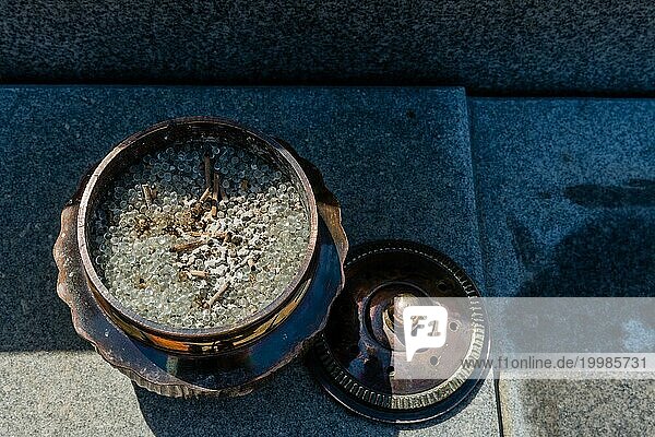 Draufsicht auf eine geöffnete  mit kleinen runden Glasperlen gefüllte Räucherschale aus Bronze auf einer Betonplatte  Südkorea  Südkorea  Asien