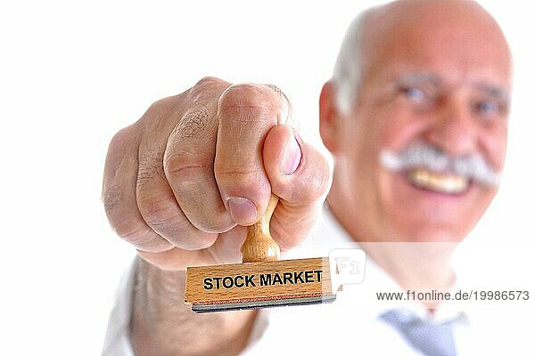 Senior  Bartträger  65  70  Jahre  Mann hält Stempel in der Hand  Aufschrift: Stock Market  Aktienmarkt  Aktien  Börse