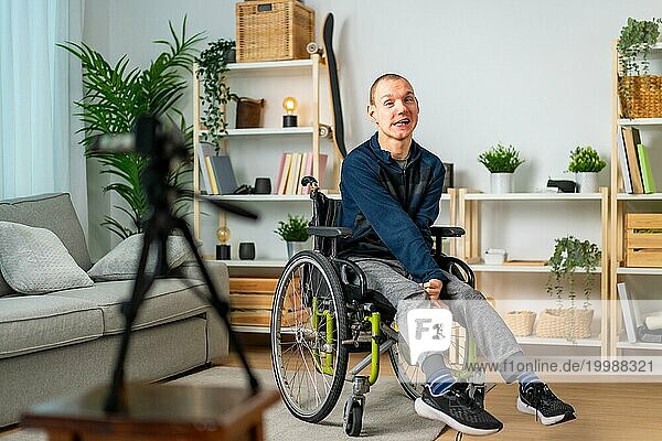 Behinderter Mann im Rollstuhl nimmt Vlog mit Digitalkamera zu Hause auf