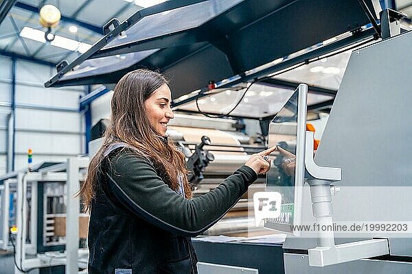 Weiblicher Arbeiter  der eine CNC Maschine zur Steuerung eines Industriekrans verwendet