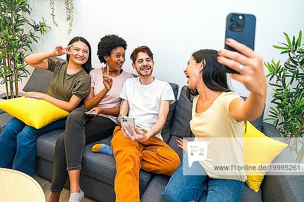 Multiethnische Freunde  die Spaß daran haben  ein Selfie zu machen  während sie zusammen auf einer Couch zu Hause sitzen
