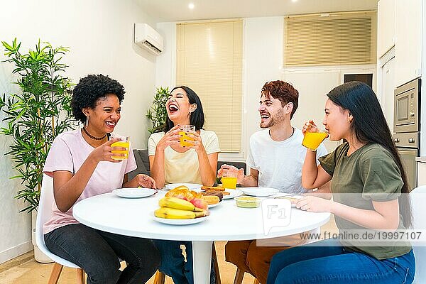 Junge multiethnische Gruppe von Freunden lacht beim gesunden Frühstück zu Hause