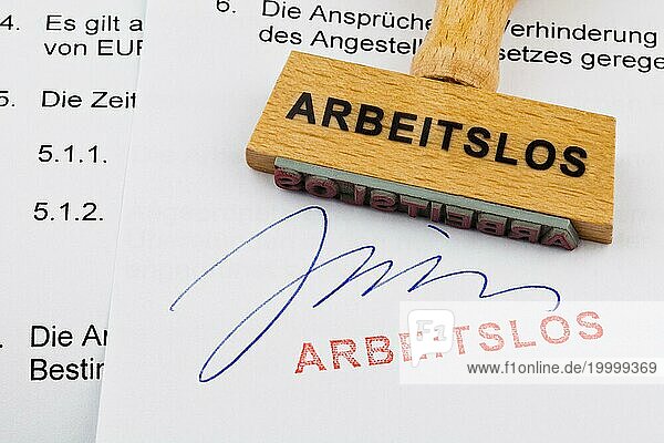 Ein Stempel aus Holz liegt auf einem Dokument. Deutsche Aufschrift: Arbeitslos