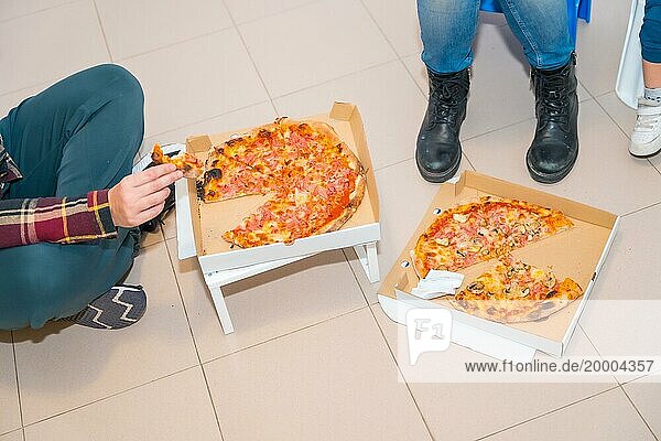 Draufsicht auf drei nicht erkennbare Personen  die in Bewegung Pizzen essen