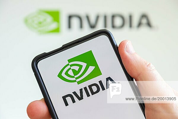 Hand holding mobile phone with Nvidia logo of the developer of graphics processors computer screen