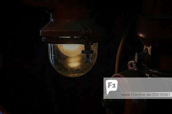 Ein stimmungsvolles Licht einer antiken Lampe in einem dunklen Teil einer Lokomotive  Bahnbetriebswerk Dahlhausen  Lost Place  Dahlhausen  Bochum  Nordrhein-Westfalen  Deutschland  Europa