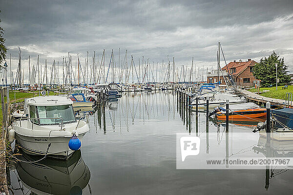 Boote liegen am Ufer der Langballigau und im Hafen des gleichnamigen Hafenortes an der Flensburger Außenförde  der Himmel ist grau  die Wolken hängen tief