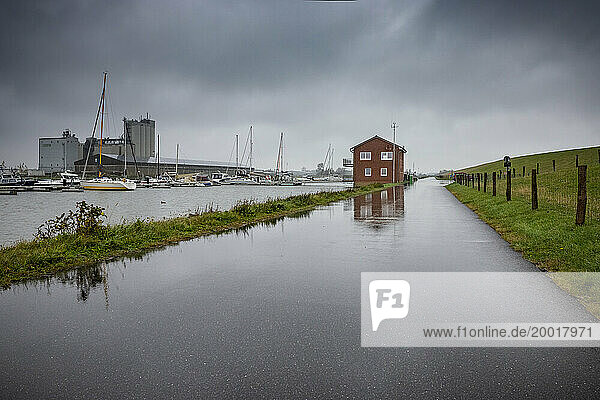 Das Clubhaus des Büsumer Seglervereins spiegelt sich auf dem regennassen Asphalt am Sportboothafen des Urlaubsortes an der Nordseeküste Dithmarschens