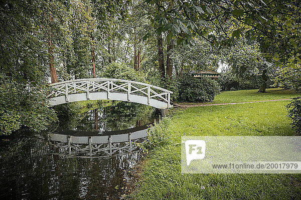 Brücke über einen Wassergraben im romantischen Klostergarten von Uetersen im Kreis Pinneberg (Schleswig-Holstein). Es ist ein regnerischer Augusttag