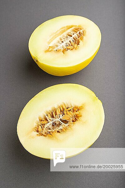 In Scheiben geschnittene reife gelbe Melone auf grauem Pastellhintergrund. Seitenansicht  Nahaufnahme. Ernte  Frauen Gesundheit  vegane Ernährung  Konzept  Minimalismus