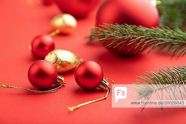 Weihnachten oder Neujahr Zusammensetzung. Dekorationen  rote Kugeln  Tannen und Fichtenzweige  auf einem roten Papierhintergrund. Seitenansicht  selektiver Fokus  Nahaufnahme