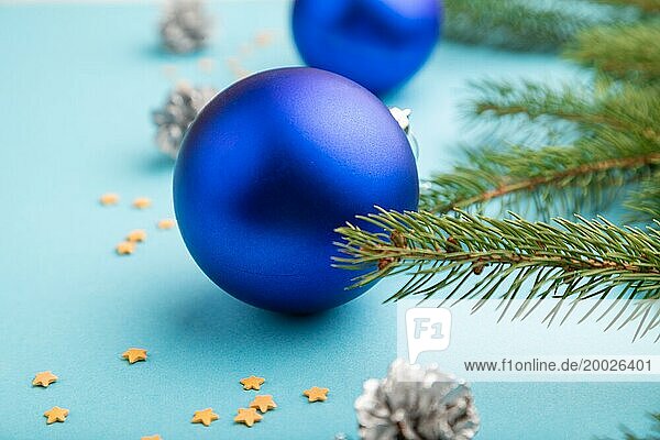 Weihnachten oder Neujahr Zusammensetzung. Dekorationen  blaue Kugeln  Zapfen  Tannen und Fichtenzweige  auf einem blaün Papierhintergrund. Seitenansicht  Nahaufnahme  selektiver Fokus