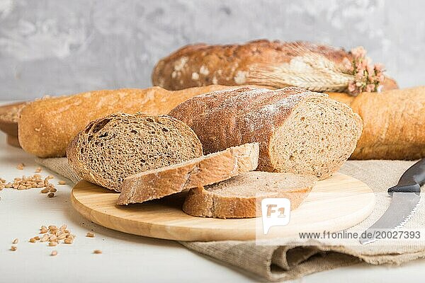 Aufgeschnittenes Brot mit verschiedenen Arten von frisch gebackenem Brot auf weißem Holzhintergrund. Seitenansicht  Nahaufnahme  selektiver Fokus