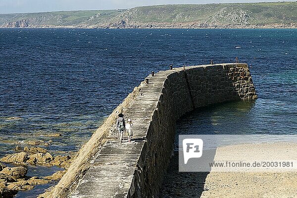 Woman and girl walking on breakwater quay  Sennen Cove  Land's End  Cornwall  England  UK