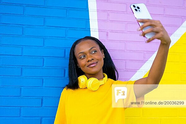 Frontal Nahaufnahme Porträt einer afrikanischen Frau lächelnd nehmen ein Selfie gegen eine bunte Wand