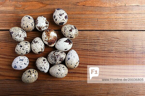 Raw quail eggs on a brown wooden background. top view with copy space