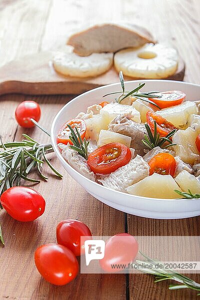 Chicken fillet salad with rosemary  pineapple and cherry tomatoes on brown wooden background. close up