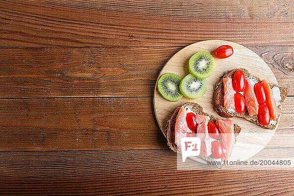 Smoked salmon sandwiches with butter on wooden background. cherry tomatoes. top view  copy space