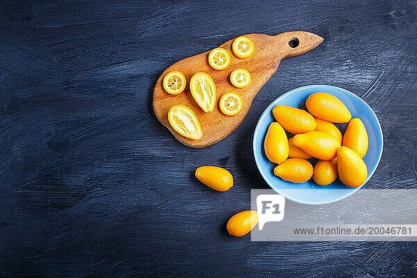 Kumquats in a blue plate on a black wooden background  top view  flat lay  copy space