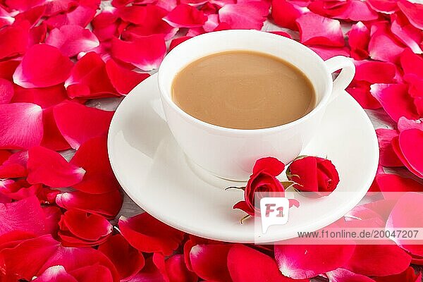 Rote Rosenblüten im Hintergrund und eine Tasse Kaffee. Morninig  Frühling  Mode Zusammensetzung. Seitenansicht  Nahaufnahme