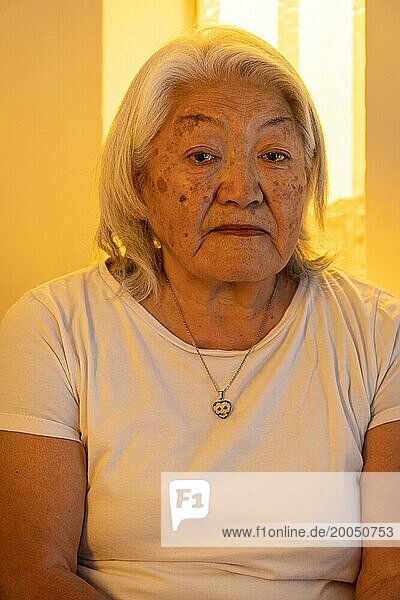 Porträt einer älteren erwachsenen Frau mit grauem Haar  die mit traurigem Gesichtsausdruck in die Kamera schaut
