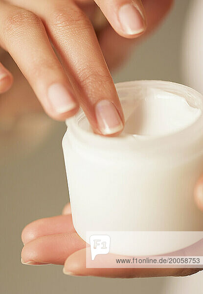 Close up of a woman's hands holding an open jar of cosmetic cream