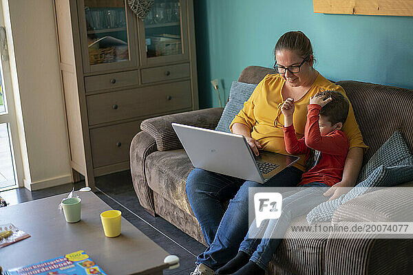 Mother sitting with her son educating him and teaching him using a laptop