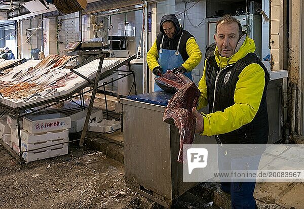 Händler  Fischhändler posiert stolz vor seinem Marktstand  zeigt zerteilten Thunfisch  Auslage frischer Fisch und Meeresfrüchte auf Eis  Food  Kapani Markt  Vlali  Thessaloniki  Makedonien  Griechenland  Europa