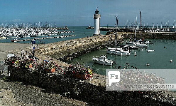 Ein ruhiger Yachthafen mit einem Leuchtturm an einem teilweise bewölkten Tag Quiberon Bretagne