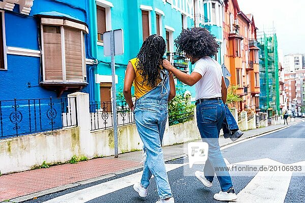 Rückansicht von zwei afroamerikanischen jungen Freunden  die eine bunte Straße entlanggehen