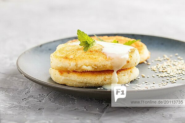 Cheese pancakes on a blue ceramic plate with milk sauce on a gray concrete background. side view  close up  selective focus