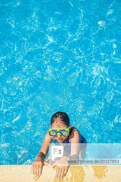 Glückliches Mädchen mit Schwimmbrille entspannt sich im Schwimmbad